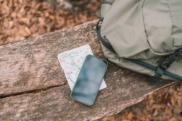 camping backpack, mobile phone, map on floor at the forest. Travel concept. vintage style. High quality photo