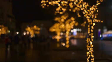 Ağaçtaki Noel ışıkları. Ağaç gövdesindeki Noel ışıkları, yakın plan. Yılbaşı ışıklarıyla bulanık arka plan şehir caddesi