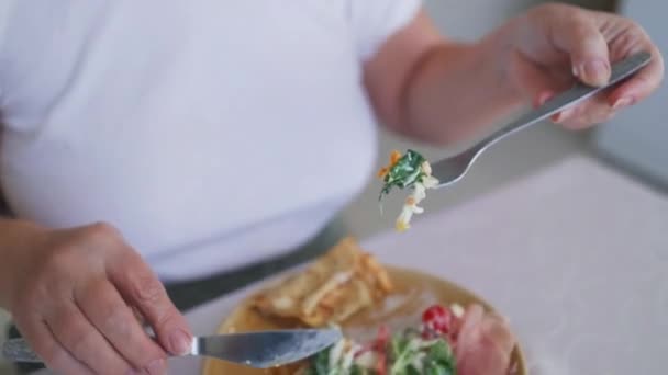 ナイフとフォークで美味しい朝食を食べる若い女性 セラミックプレートのフライドエッグ フレッシュサラダ パンケーキ 高品質のフルHd映像 — ストック動画
