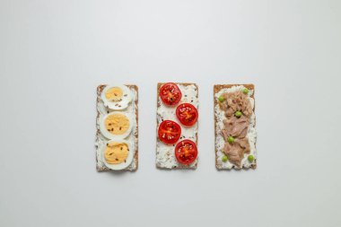 Haşlanmış yumurtalı sandviç, vişneli domates, konserve ton balığı, sarımsak ve baharatlar için gri arka planda. Yüksek kalite fotoğraf