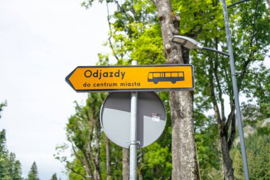 Sarı metal levha, dağlardaki yolcular için otobüslerin kalkışı hakkında bilgi içeriyor. Zakopane, Polonya