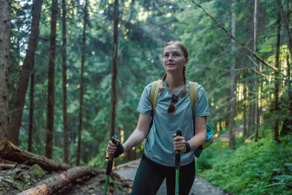 Sırt çantasıyla ormanda gezen gezgin kadın yaz ormanlarında güneşin doğuşunun tadını çıkarıyor.