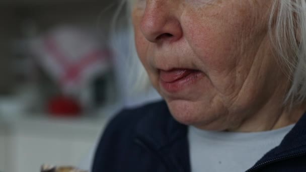 在一个秋天的早晨 一位穿着白色T恤的快乐的六十岁老妇人在家里吃着美味的提拉米苏 喝着一杯咖啡拿铁 优质Fullhd影片 — 图库视频影像