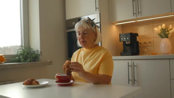 매력적인 활기찬 코카서스 배고픈 여자는 부엌에서 테이블에 초콜릿 식사와 크로이센트를 — 비디오