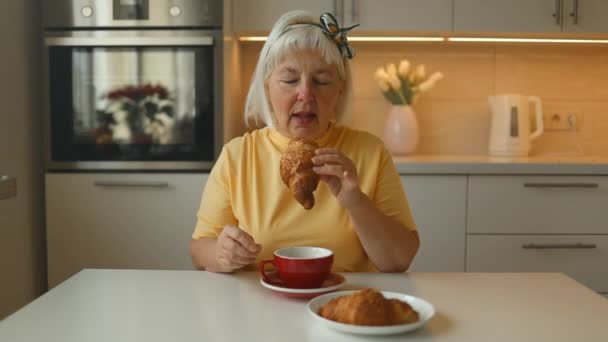 Çekici Enerjik Yaşlı Beyaz Yaşlarda Bir Kadın Kahvaltıda Çikolatalı Kruvasan — Stok video