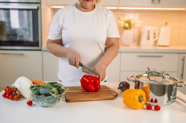 Kesme tahtası ve mutfakta çan biberli sebze kesen, evde yemek hazırlayan bir kadın resmi. Vejetaryen sağlıklı yiyecekler. Yüksek kalite fotoğraf