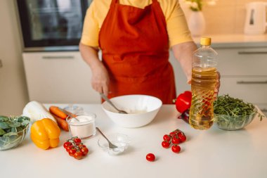 Kadın mutfakta yemek hazırlarken sebze salatası hazırlıyor. Tanınmayan şef evde vejetaryen yemeği hazırlarken zeytinyağı ekliyor. Sağlıklı yeme kavramı. 