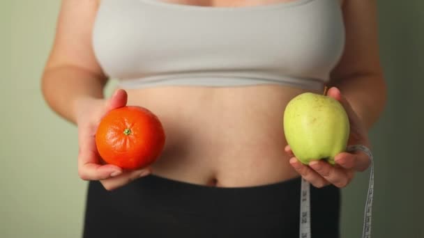 黒いパンティーで太りすぎの女性のクロップショット リンゴとオレンジでルーレットテープヒップで測定 大きいサイズの脂肪胃 ダイエットの結果 不健康な肥満問題 不釣り合い しようとしている — ストック動画