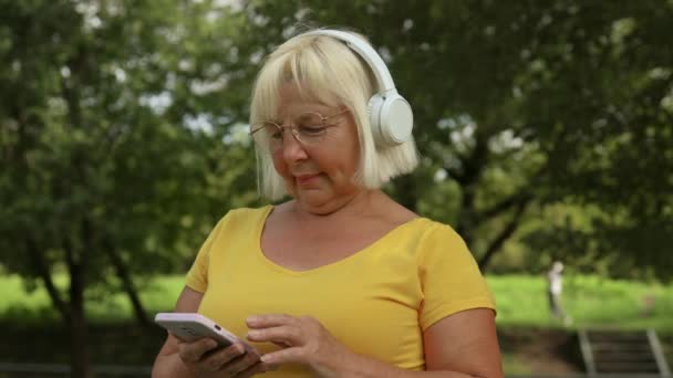 Wanita Tua Yang Bahagia Berjalan Taman Dan Mendengarkan Musik Dengan — Stok Video