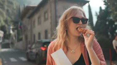 Açık havada limon ricotta kremalı geleneksel Sicilyalı kanoli yiyen mutlu sarışın kadın. Como, İtalya. Sokak yemeği. 