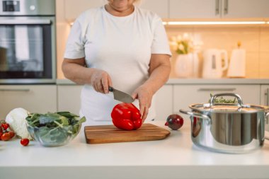 Kesme tahtası ve mutfakta çan biberli sebze kesen, evde yemek hazırlayan bir kadın resmi. Vejetaryen sağlıklı yiyecekler. Yüksek kalite fotoğraf