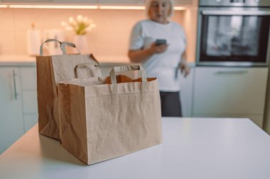 Çevrimiçi ev yemeği servisi. İnternetten sipariş listesini kontrol eden bir kadın. Genç bir kadın evde yiyecek kutularını açıyor. Sağlıklı bir hayatın başlangıcı. 