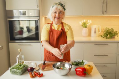 Son sınıf öğrencisi kadın mutfakta sebze salatası hazırlıyor. Kadın salataya roka ekliyor. Sağlıklı yiyecekler. Vejetaryen salatası. Diyet olsun. Diyet Konsepti. Sağlıklı yaşam tarzı. Evde yemek pişirmek. Yemek hazırlayın.