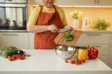 Elinde bıçak ve taze ıspanak tutan 60 'lı yılların son sınıf sarışın beyaz kadın kırsal mutfağında bir kase sağlıklı diyet salatası hazırlıyor. Yüksek kalite fotoğraf