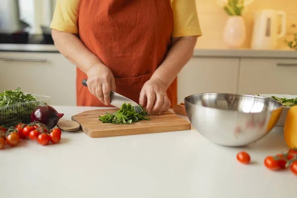 Woman hands cutting vegetables in the kitchen.Close up cropped image of female cutting board cutting vegetables in the kitchen, preparing food meal at home. Vegetarian healthy food