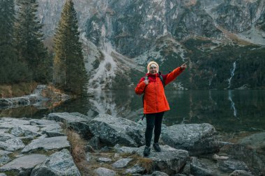 Sırt çantalı bayan turist dağın tepesinde duruyor ve Morskie Oko Gölü 'nün güzel manzarasının tadını çıkarıyor. Polonya 'da yürüyüş ve macera, Tatry 
