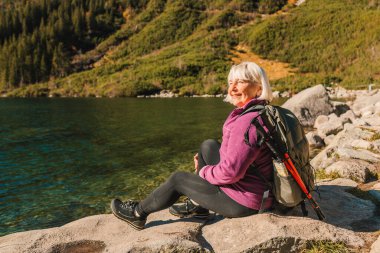 Sırt çantalı bayan turist dağın tepesinde duruyor ve Morskie Oko Gölü 'nün güzel manzarasının tadını çıkarıyor. Polonya 'da yürüyüş ve macera, Tatry 