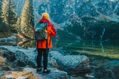 60 'lı yaşlarda akıllı telefonlu, elinde haritayla bir dağın tepesinden manzarayı seyreden kayıp bir kadının fotoğrafı. Dişi turist dağdaki kayada oturuyor ve haritayı okuyor. Polonya, Tatry 