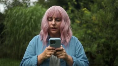 Sinirli, mutsuz, beyaz saçlı bir kadının portresi. Şehir caddesinde telefonuna mesaj geldiğinde rahatsız oluyor. Dışarıdaki akıllı telefonlardan rahatsız olan bir kadın. Yüksek