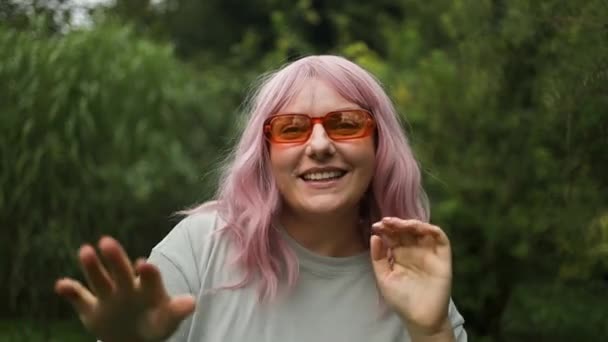 在公园里 戴着橙色太阳镜 长着牙齿 一头粉色头发的女人跳着春天的舞曲 — 图库视频影像