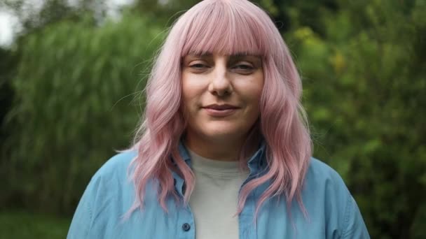 夏の庭で屋外のカメラでかわいい魅力的なピンクの髪の女性の笑顔の写真を閉じます 高品質のフルHd映像 — ストック動画