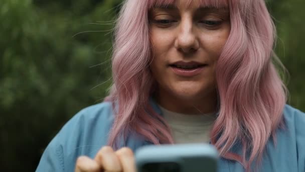 快乐的粉红头发的年轻白种人30多岁的女人用手机做得奖手势并获奖 优质Fullhd影片 — 图库视频影像