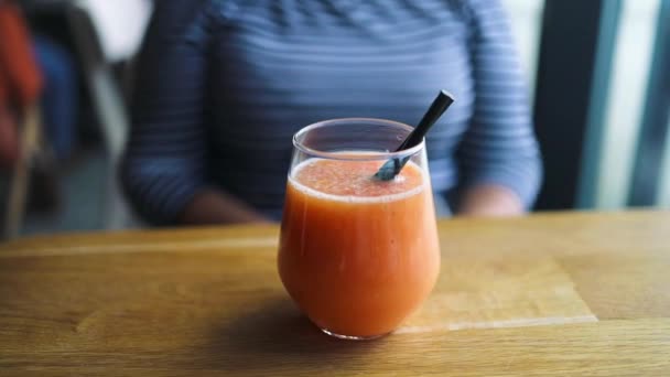 外面的咖啡馆里喝着一杯甜瓜柠檬水 夏天喝的在餐馆里享受的女人 城市咖啡店木制桌子上的玻璃杯中新鲜橙汁 — 图库视频影像