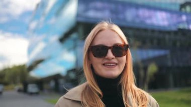 Güneş gözlüklü, gülümseyen beyaz kadın portresi. Dışarıda kameraya bakıyor. Mutlu bir iş kadını gibi. 