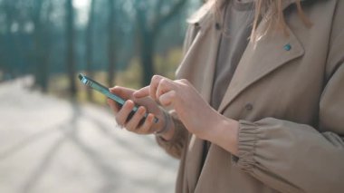 İş kadını elleri gözlüklü Central City caddesinde yürüyor ve telefonunu bir alışveriş merkezinin arka planında kullanıyor..