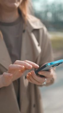 Gülümseyen gözlüklü iş kadını Central City caddesinde yürüyor ve bir alışveriş merkezinin arka planında telefonunu kullanıyor..