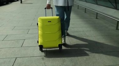 Terminalde yürüyen ve tekerlekli bavulu çeken bir gezginin ayakları. Genç iş adamının bacakları bavuluyla içeri giriyor. İş gezisi kavramı. Yüksek kaliteli FullHD görüntüler