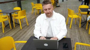 Yakışıklı beyaz üniversiteli çocuk dizüstü bilgisayar kullanarak uzaktan eğitim semineri, uzaktan üniversite webinarı ya da açık havada sanal sınıf toplantısı yapıyor.