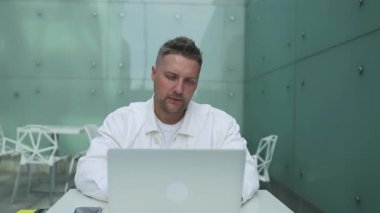 Havalimanında dizüstü bilgisayarla oturup ekrana bakan 30 'lu yaşlardaki yakışıklı beyaz adam. Uluslararası havaalanında kalkış için beklemede..