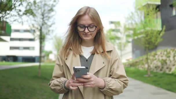 Uśmiechnięta Kobieta Biznesu Modnych Okularach Idzie Ulicą Centralną Używa Telefonu — Wideo stockowe