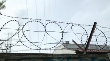 Yağmurlu bir günde hapishanenin dikenli telleriyle elektrikli tel örgülerin genel görünümü. Çitlere yağmur damlaları yağıyor. Yüksek kaliteli FullHD görüntüler
