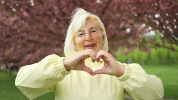 Smiling Happy Caucasian Blonde Senior Showing Heart Two Hands Love — Stock Video