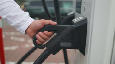 Elektrikli arabanın şarj istasyonundan fişini çeken tanınmamış bir adam. Erkek gün batımında elektrikli bir arabaya elektrik kablosu takıyor. Kafkasyalı işadamı şarj istasyonunda elektrikli araba şarj ediyor. Yüksek