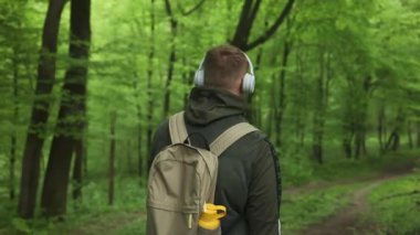 Kafkasyalı mutlu adam parkta kulaklıkla cep telefonundan müzik dinliyor. Yüksek kaliteli FullHD görüntüler