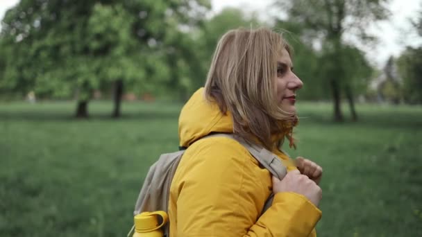 屋外の森を歩く明るい黄色いジャケットを着た若い女性のバックビュー ツーリストウォーク 自然のレクリエーション 秋の森での冒険 レジャー活動を楽しむ 健康的なライフスタイル — ストック動画