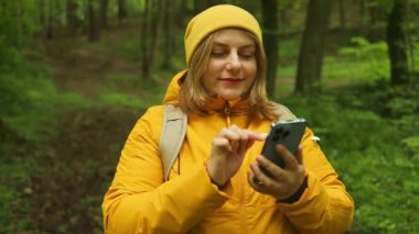 Gezgin Kafkasyalı 30 'lu yaşlarda kadın spor kıyafetleri içinde Eko Ormanı' nda durup akıllı telefon kullanmaktan mutlu oluyor. Polonya 'da yürüyüş ve macera, Tatry 