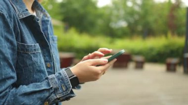 Çekici genç kız şehirde akıllı telefon kullanıyor. Gün batımında yürüyor. Etrafına bak.