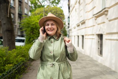 Şık bir kadın arıyor ve akıllı telefondan konuşuyor. Güneşli bir günde şehir bahçesinde cep telefonu olan bir kız. Yüksek kalite fotoğraf