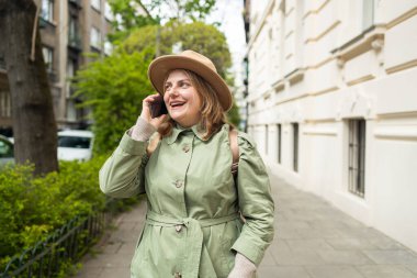 Şık bir kadın arıyor ve akıllı telefondan konuşuyor. Güneşli bir günde şehir bahçesinde cep telefonu olan bir kız. Yüksek kalite fotoğraf