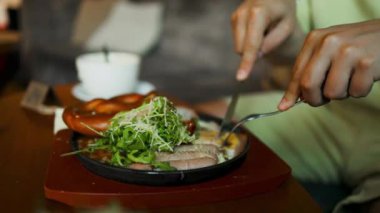 Sağlıklı sabah yemeği. Otel kafesinde nefis yumurtalar yiyen bir adam. Erkek, yumurta sarısı, hollandez sosu ve salata ile yumurta kesmek için çatal ve bıçak kullanır. Kapatın. Yüksek kalite 4k