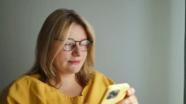 Ofiste çalışan gülümseyen 30 'ların iş kadını yöneticisi. Akıllı telefon tutan mutlu iş kadını, iş yerinde cep telefonuna bakan profesyonel kadın yönetici. Yüksek kalite FullHD