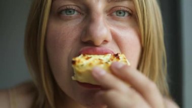 Gözleri kapalı, yemek yerken tadını çıkaran genç bir kadın yüksek kaliteli FullHD görüntülerini kapatıyor.