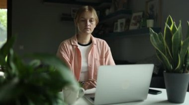 Şık giyinmiş, beyaz bir kız öğrenci bilgisayarında ağır çekimde antrenman yapıyor. Yüksek kaliteli FullHD görüntüler