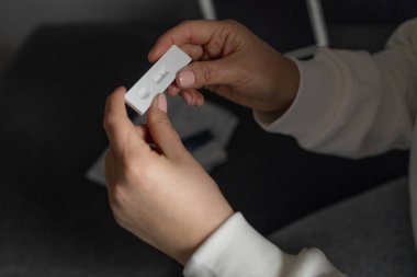 Beyaz kadın evde COVID-19 salgını için hızlı antijen test kiti kullanıyor. Yetişkin dişi burnuna sokmak için bir bez çıkarıyor. COVID-19 koronavirüs pandemik koruma kavramı. 