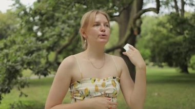 Genç bir kadın sıcak bir yaz gününde terliyor. Sıcak havada kağıt peçeteyle kuruyan bir kadın. Yüksek kaliteli FullHD görüntüler