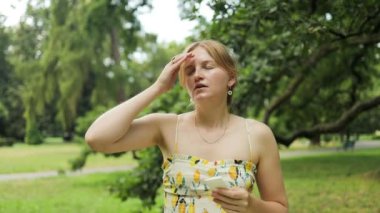 Genç bir kadın sıcak bir yaz gününde terliyor. Sıcak havada kağıt peçeteyle kuruyan bir kadın. Yüksek kaliteli FullHD görüntüler